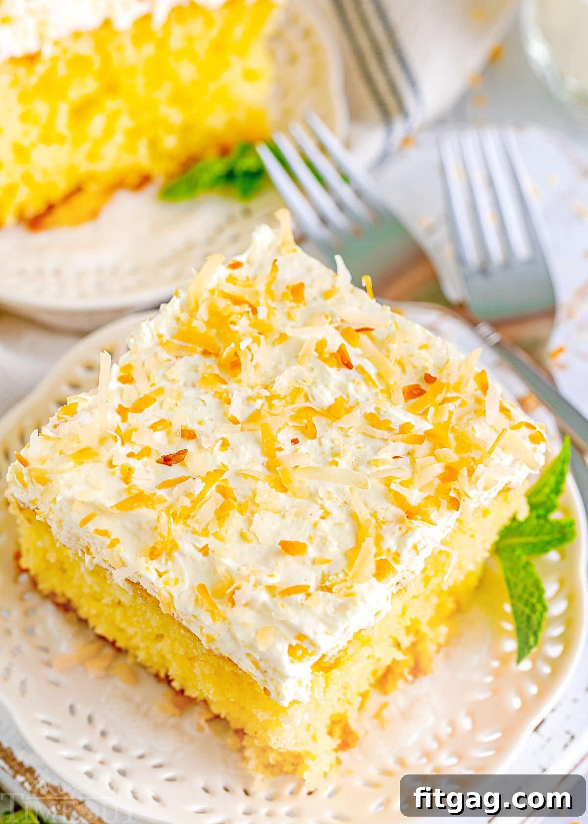 A high-angle view of the frosted Pina Colada Cake, beautifully topped with a generous sprinkle of golden toasted coconut flakes, showcasing its enticing texture and presentation.