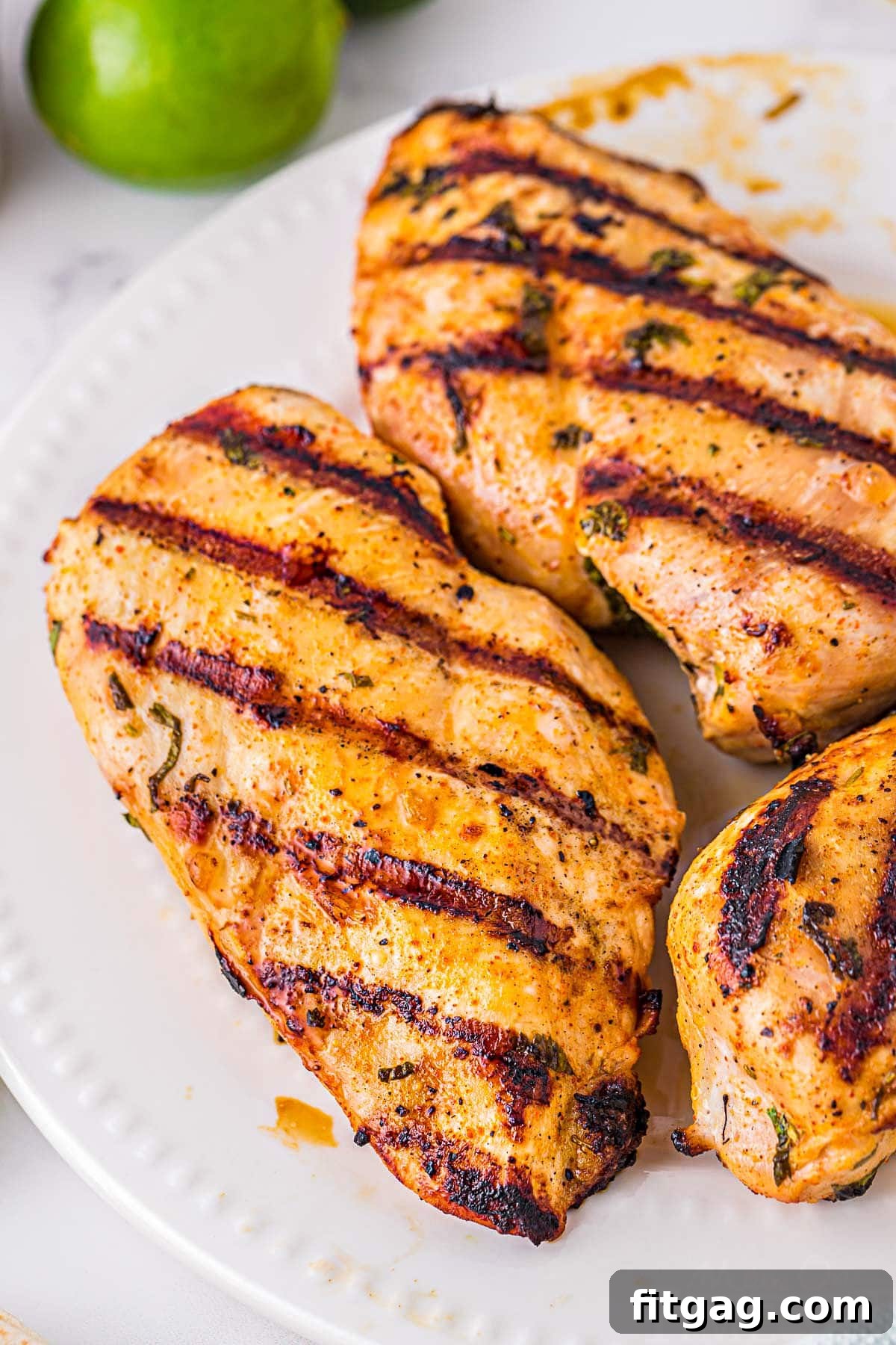 three grilled chicken breasts on white plate that were marinated in a cilantro lime marinade.