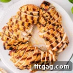 white plate with grilled chicken breasts cut into slices arranged in a circular pattern. Limes can be seen next to the plate.