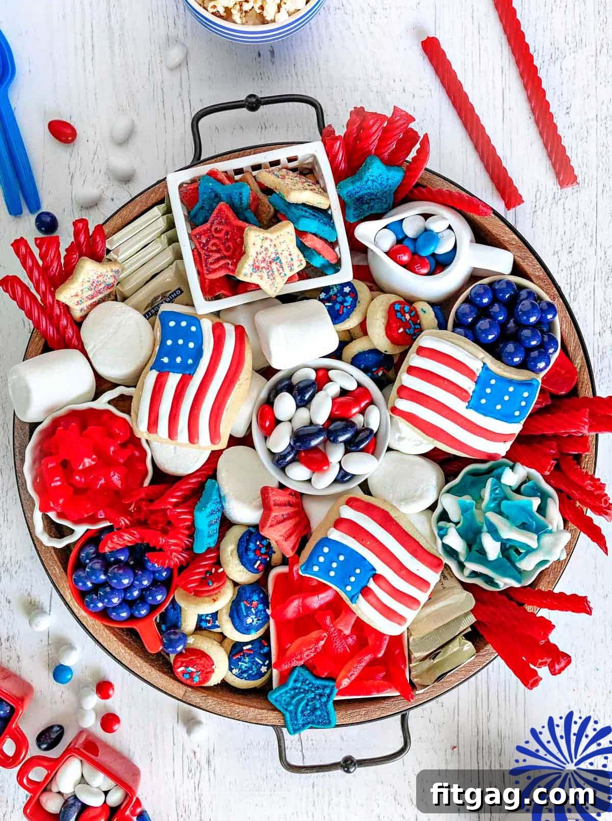 Stars and Stripes Grazing Board 2 A beautifully arranged 4th of July dessert charcuterie board from a top-down view, featuring an abundance of red, white, and blue candies, cookies, and other sweet treats on a rustic wooden board.