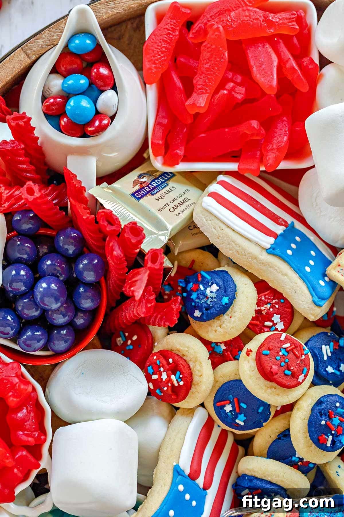 Stars and Stripes Grazing Board 5 A close-up, top-down view of a festive 4th of July dessert board, showcasing a vibrant array of cookies and treats artfully arranged on a large round wooden board.