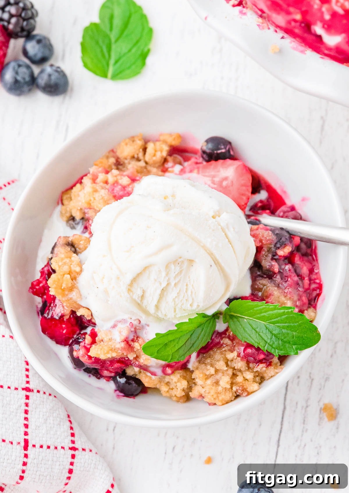 Top-down view of a white bowl filled with berry crisp and topped with vanilla ice cream, creating a delightful visual.