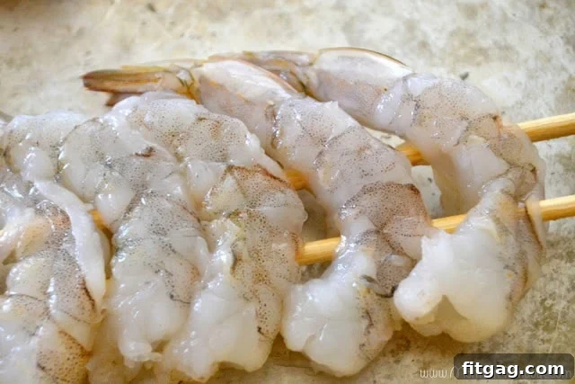 Double-skewered raw shrimp arranged for marinating with lime slices