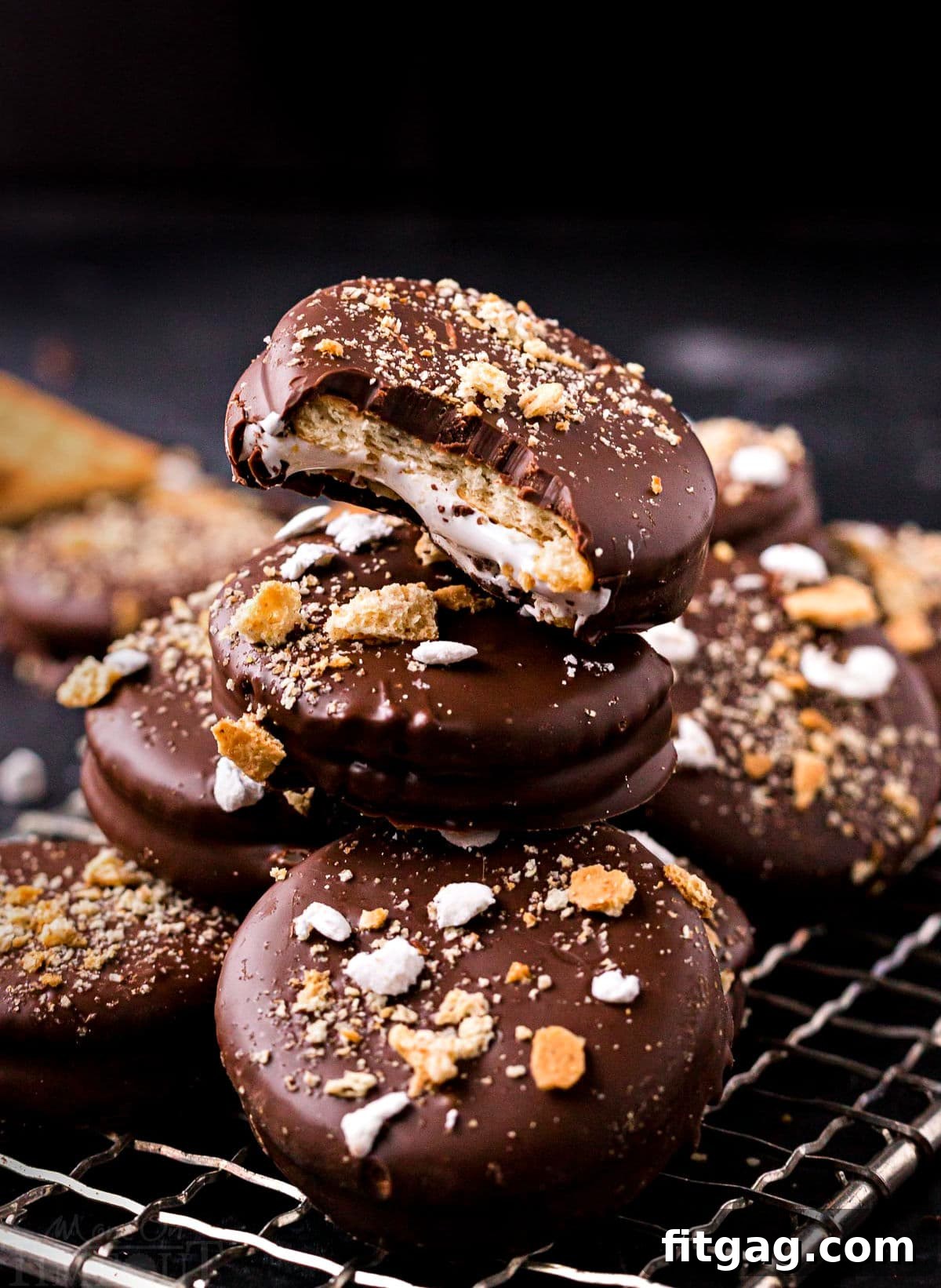 Ritz Smores Cookie Mashup 2 no bake ritz cracker sandwich cookies with marshmallow filling and dipped in chocolate stacked on small wire rack. tops of cookies have crushed graham crackers and miniature marshmallows.