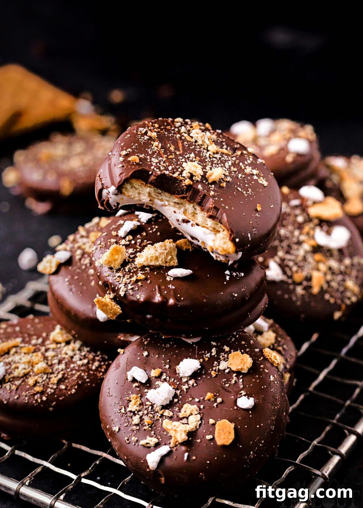 Ritz Smores Cookie Mashup 6 no bake ritz cracker sandwich cookies with marshmallow filling and dipped in chocolate stacked on small wire rack. tops of cookies have crushed graham crackers and miniature marshmallows.