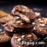 Ritz Smores Cookie Mashup 7 no bake ritz cracker sandwich cookies with marshmallow filling and dipped in chocolate stacked on small wire rack. tops of cookies have crushed graham crackers and miniature marshmallows.