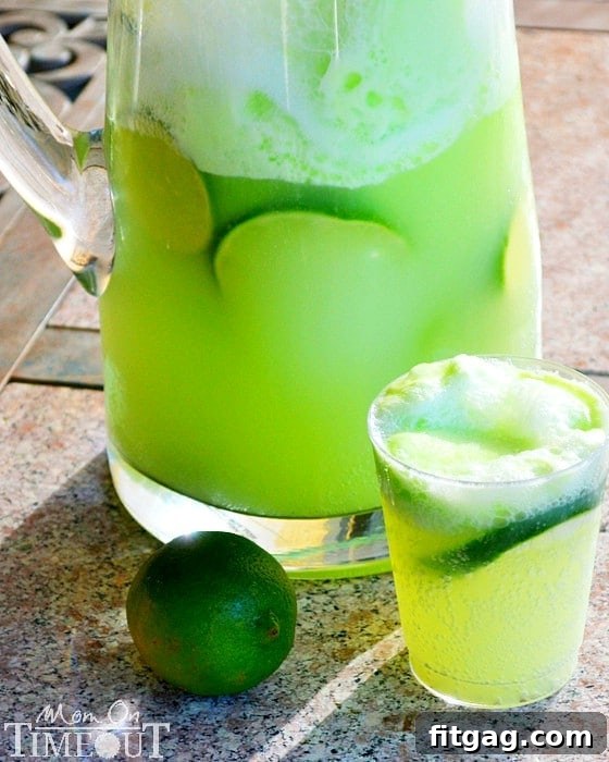 Full view of the vibrant green Lemon Lime Party Punch in a decorative punch bowl with lime slices.