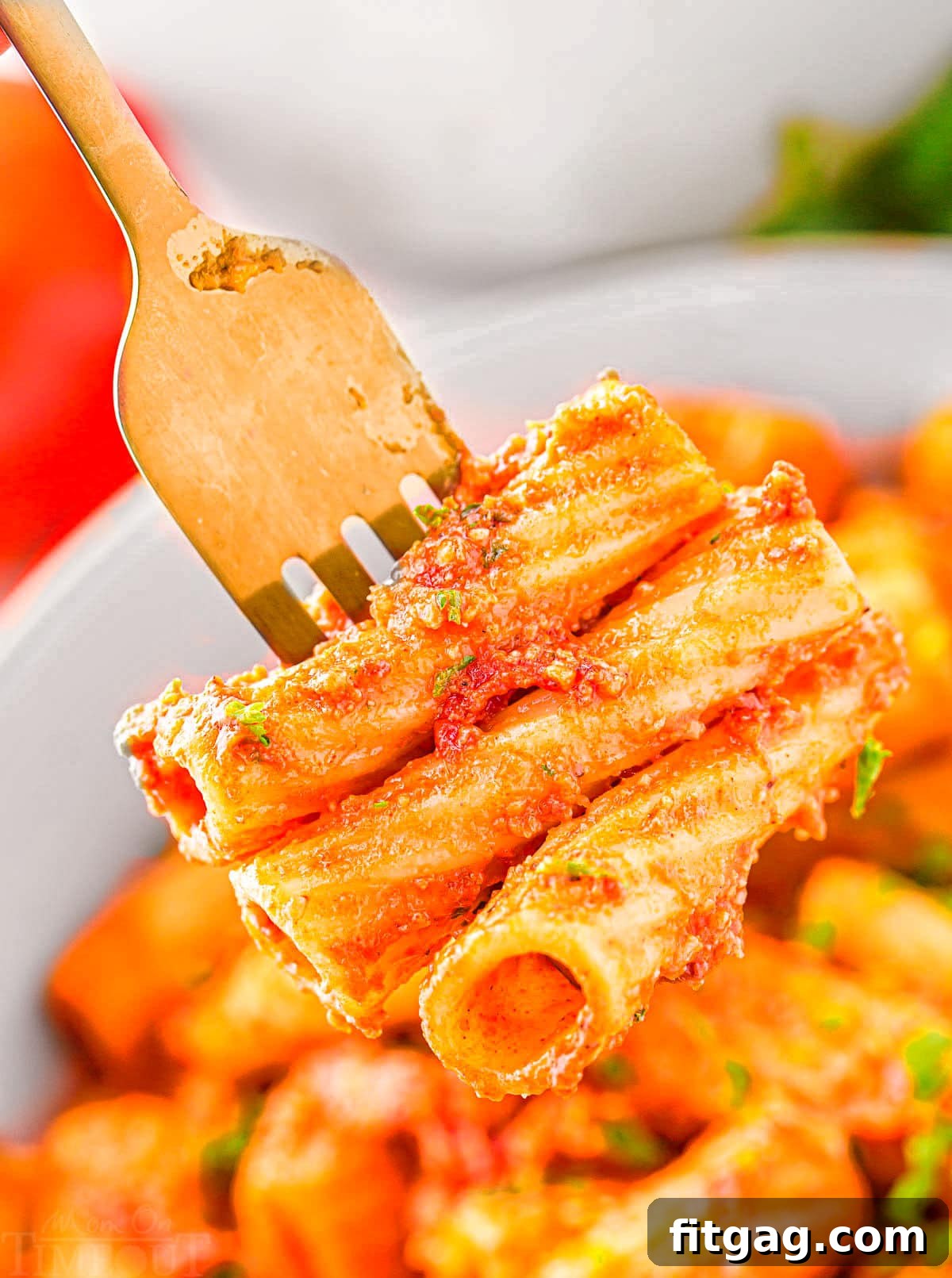 fork with three pieces of pasta on it held above a bowl.