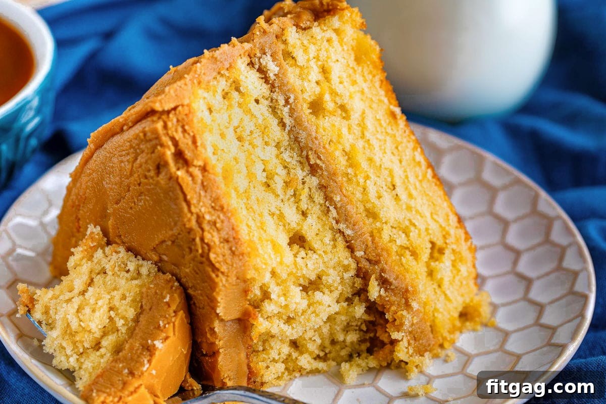 A delectable slice of caramel layer cake on a pristine white plate, with a fork gently resting on the side, showcasing the moist layers and luscious frosting.