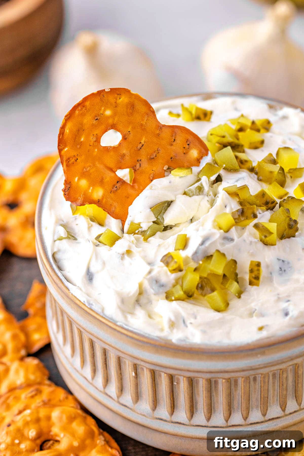 Creamy Dill Pickle Dip 7 pretzel chip being dipped into a small bowl filled with pickle dip.