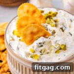 Creamy Dill Pickle Dip 8 small clay bowl with dill pickle dip in it. three crackers are dipped into the dip with a sprinkle of chopped pickle scattered on top.
