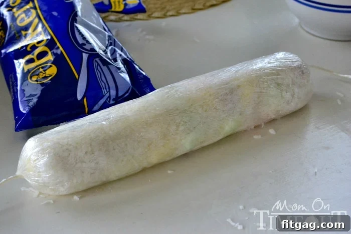 A finished log of Easter Cathedral Candy, tightly wrapped in plastic wrap and ready for chilling.
