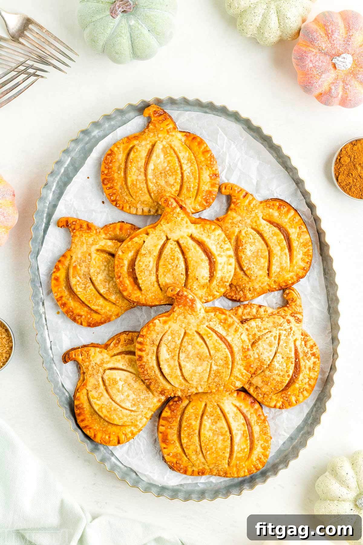 Pumpkin Pie Pockets 3 A top-down view of beautifully arranged pumpkin hand pies on a rustic metal platter, ready to be served and enjoyed.