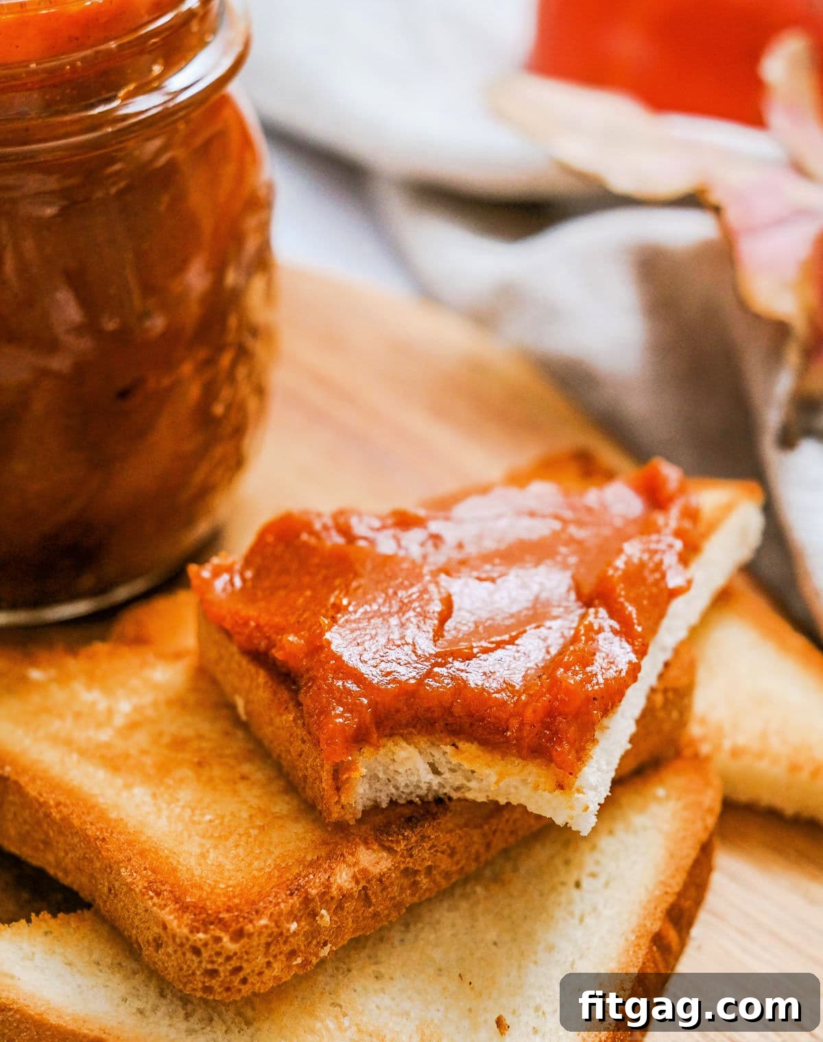 stack of toast with top piece cut into triangle and smeared with pumpkin butter. jar of pumpkin butter can be seen to the side.