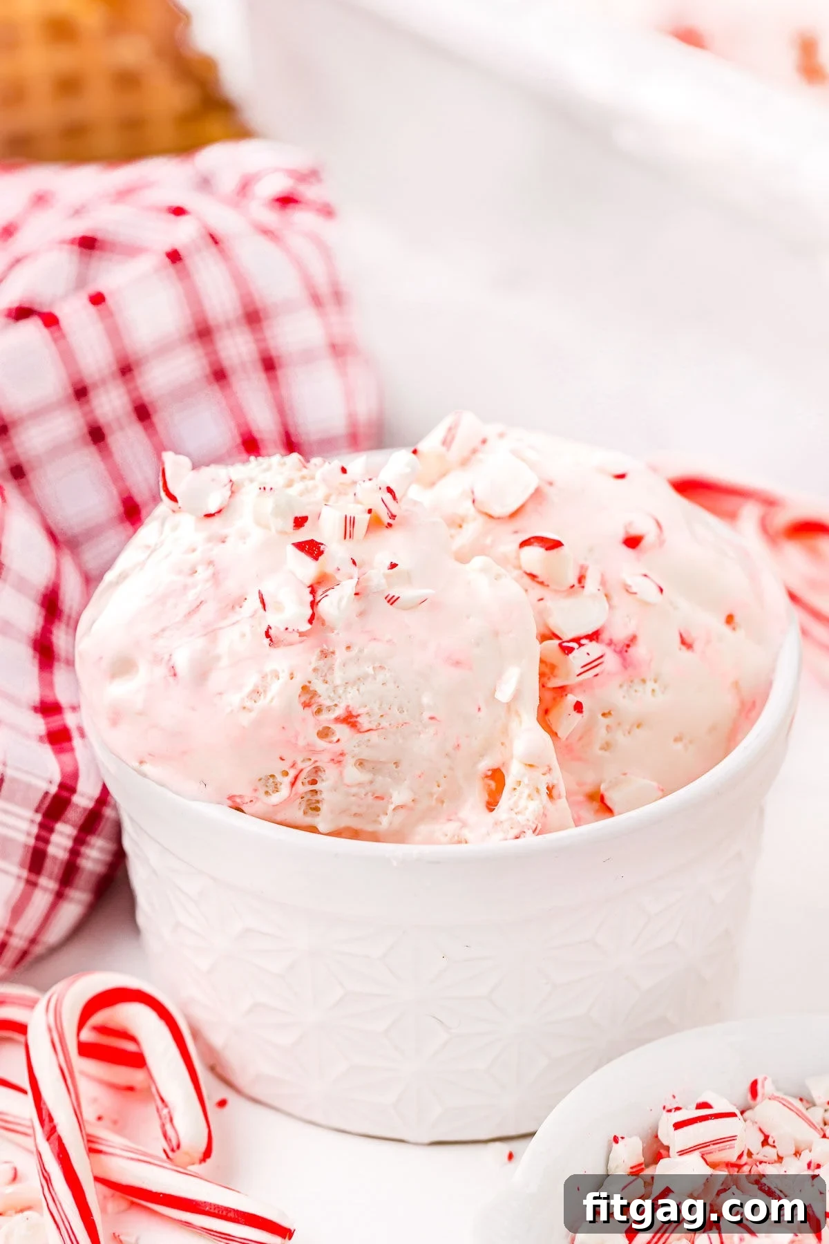 A beautifully presented white bowl of Peppermint Ice Cream, generously sprinkled with miniature candy canes, invoking a festive winter mood.