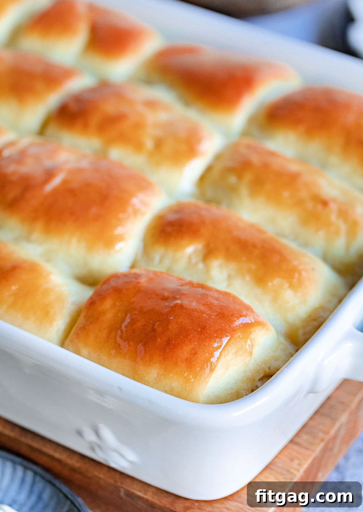 golden brown parker house rolls slathered with butter and still in the white baking dish.