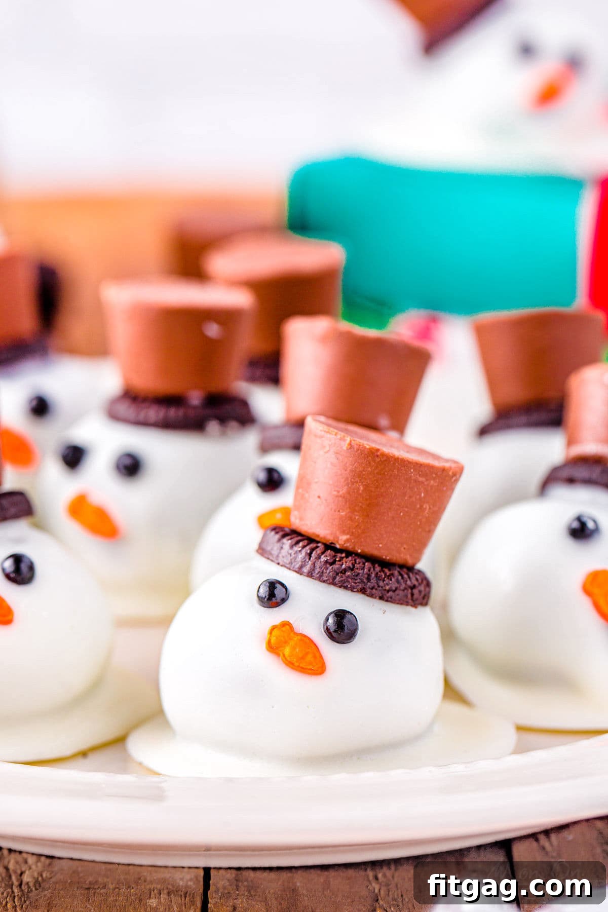 Disappearing Snowman Oreo Truffles 2 melting snowman oreo balls on a white plate topped with mini oreos and rolo candy.