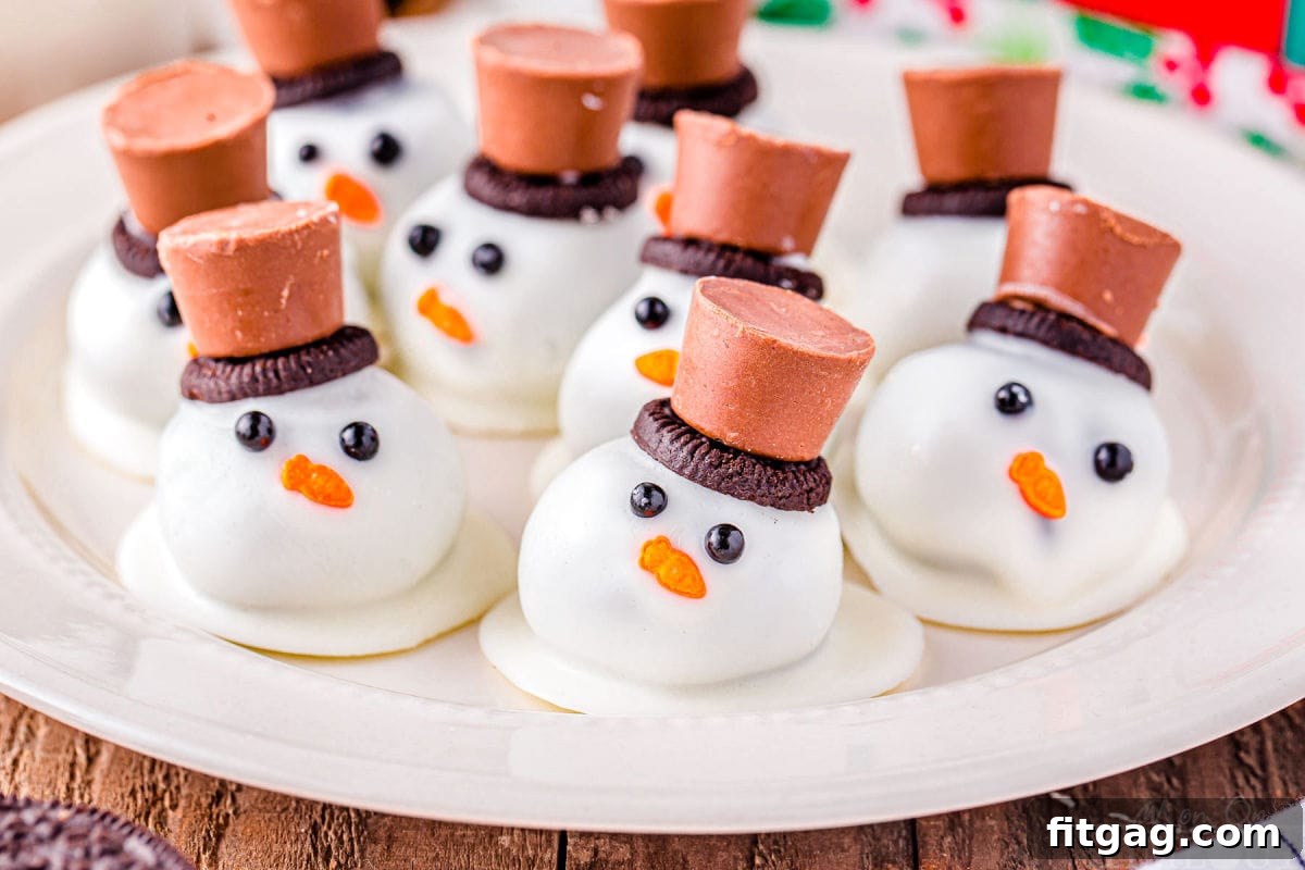 Disappearing Snowman Oreo Truffles 5 melting snowman oreo balls on a white plate topped with mini oreos and rolo candy.