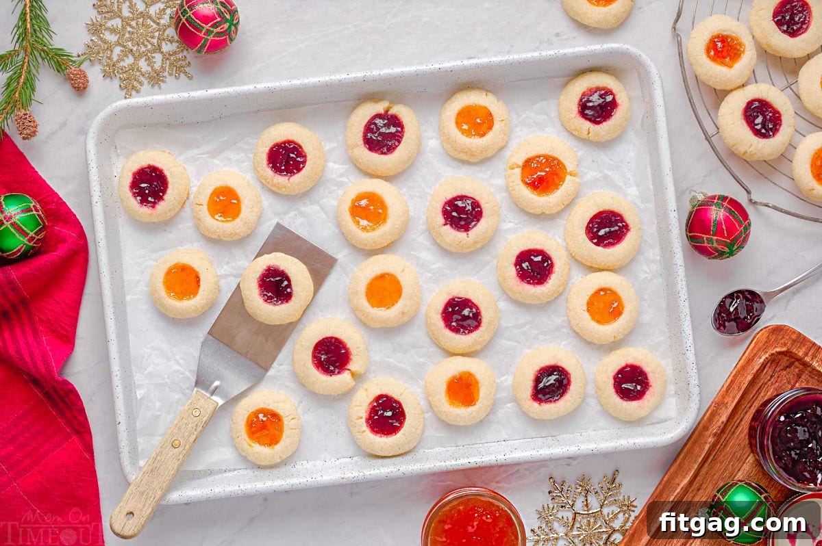 thumbprint cookies on a parchment lined baking sheet with spatula lifting off one cookie.