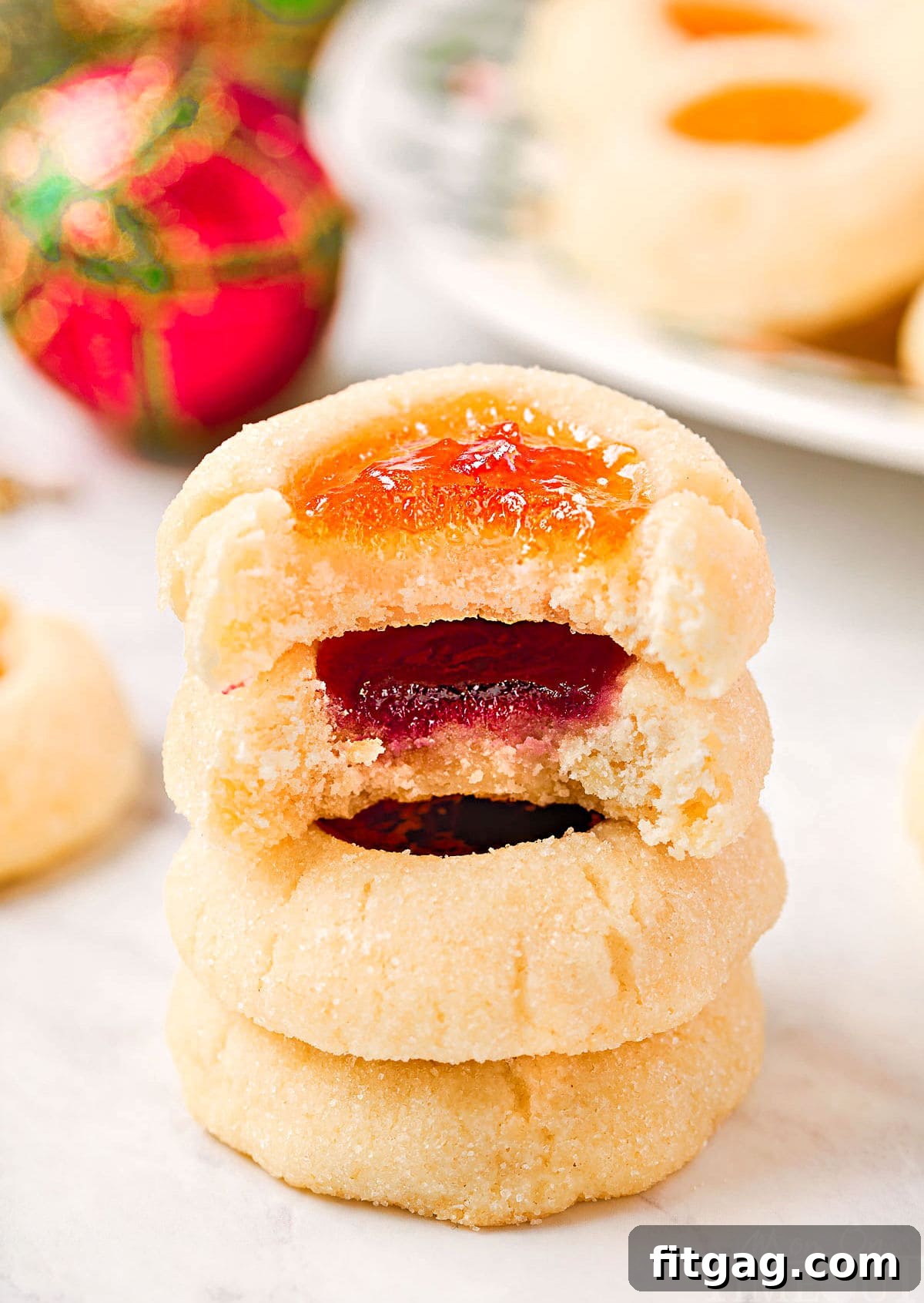 four cookies stacked with jam centers. top two cookies have bites taken out of them.