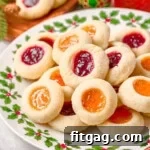 christmas plate piled high with thumbprint cookies filled with apricot and raspberry jam.