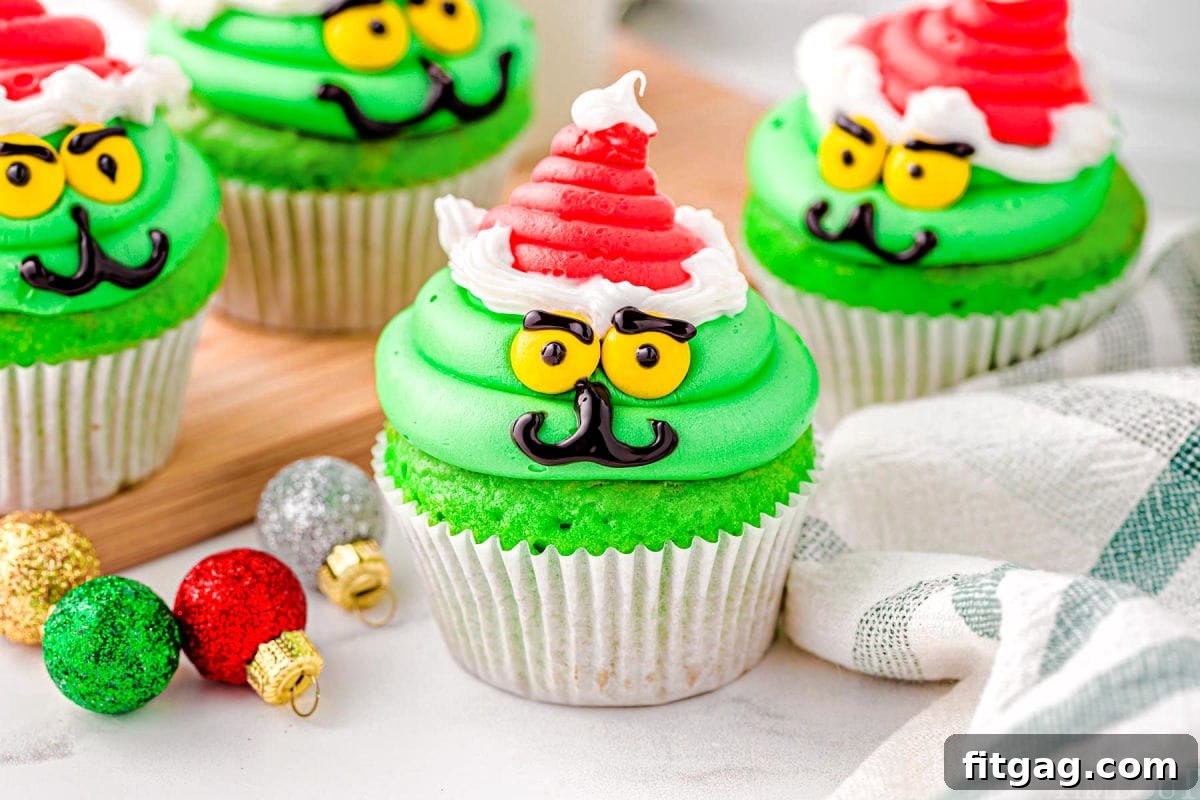 wide shot of four grinch cupcakes in white cupcake liners all decorated and ready to be enjoyed.