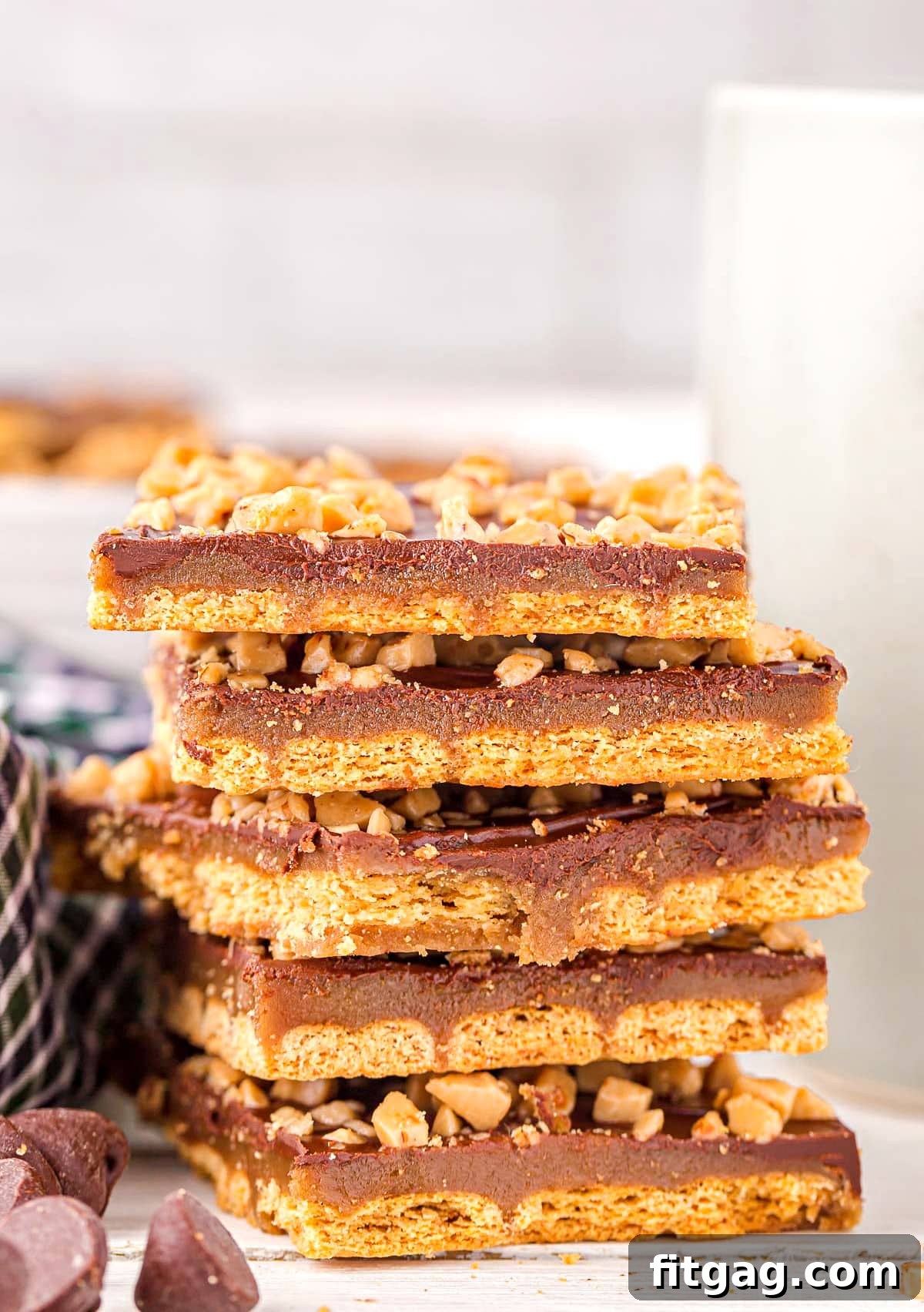 Decadent Graham Toffee Bark 2 six pieces of graham cracker toffee stacked on top of each other with some chocolate chips scattered in front.