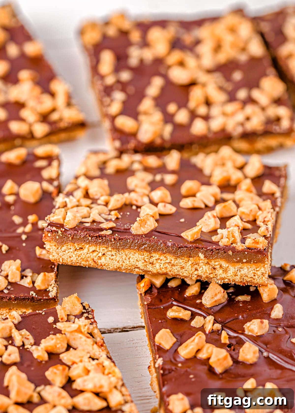Decadent Graham Toffee Bark 3 graham cracker toffee laid out on parchment with one square sitting up at an angle.