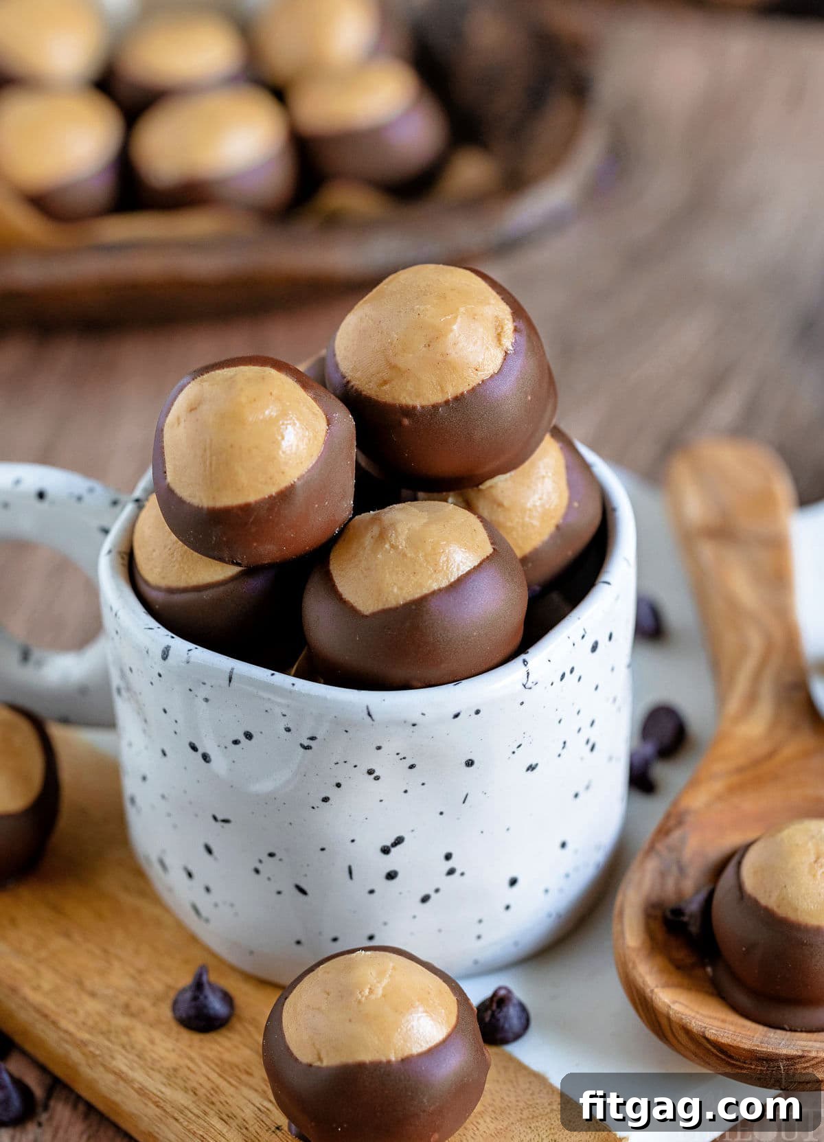 Ohio's Buckeye Story 2 A charming white mug brimming with buckeye candy, nestled on a pristine white marble surface. Additional buckeyes are artfully scattered in the background.