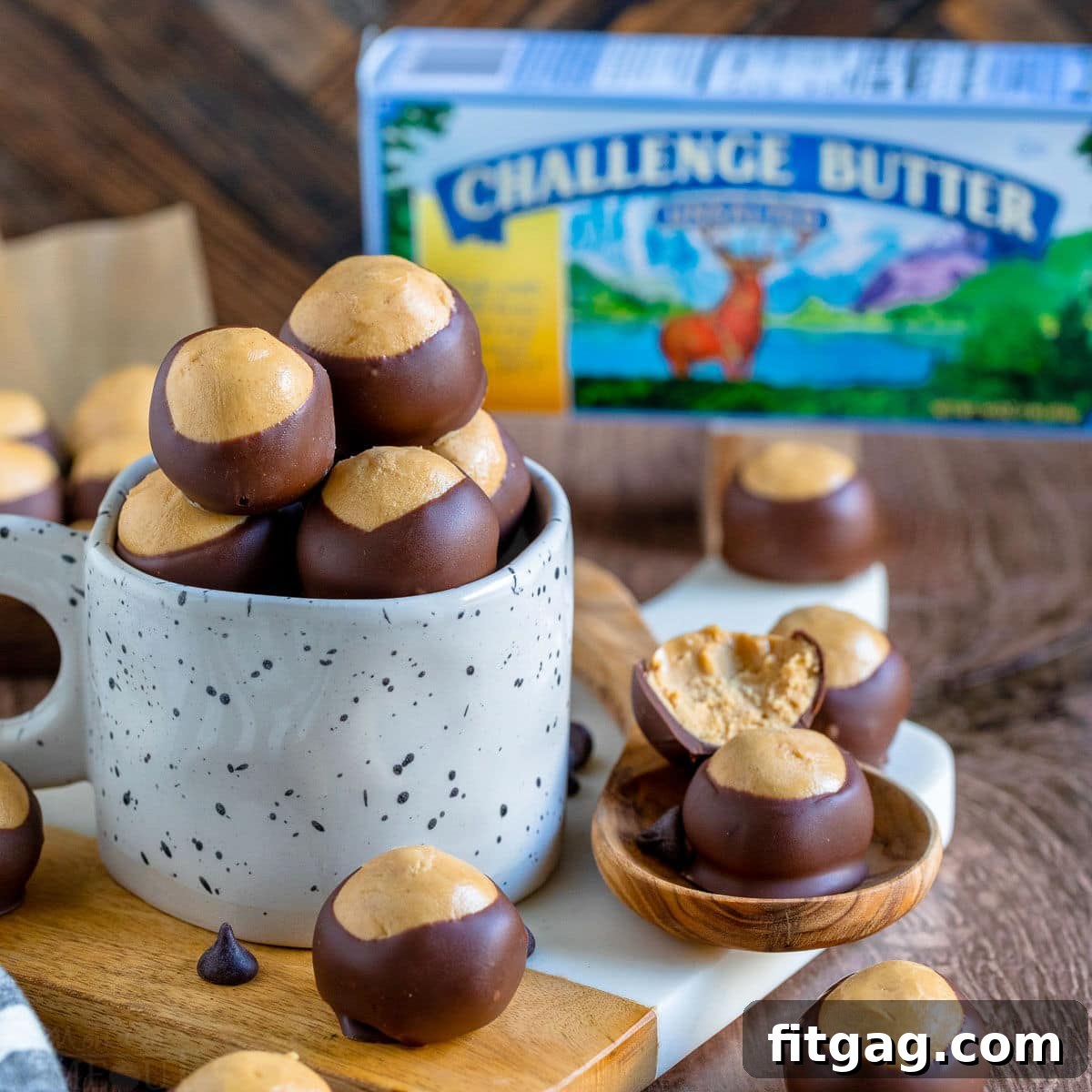 Ohio's Buckeye Story 4 A beautiful array of buckeye candy, ready for enjoyment, presented in a pristine white clay mug and alongside it on a elegant white marble cutting board. In the softly blurred background, a recognizable box of Challenge butter can be seen.