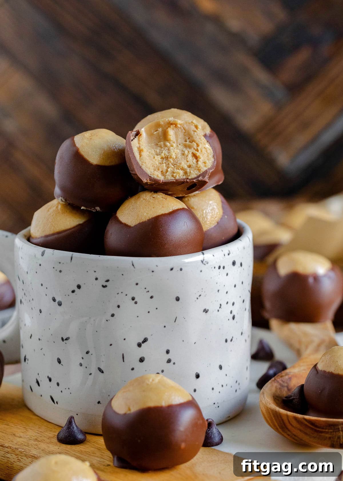Ohio's Buckeye Story 8 A white mug thoughtfully filled with buckeye candy rests on a pristine marble cutting board. More buckeyes are visible in the background and foreground, with one buckeye in the mug revealing a tantalizing bite taken out of it.