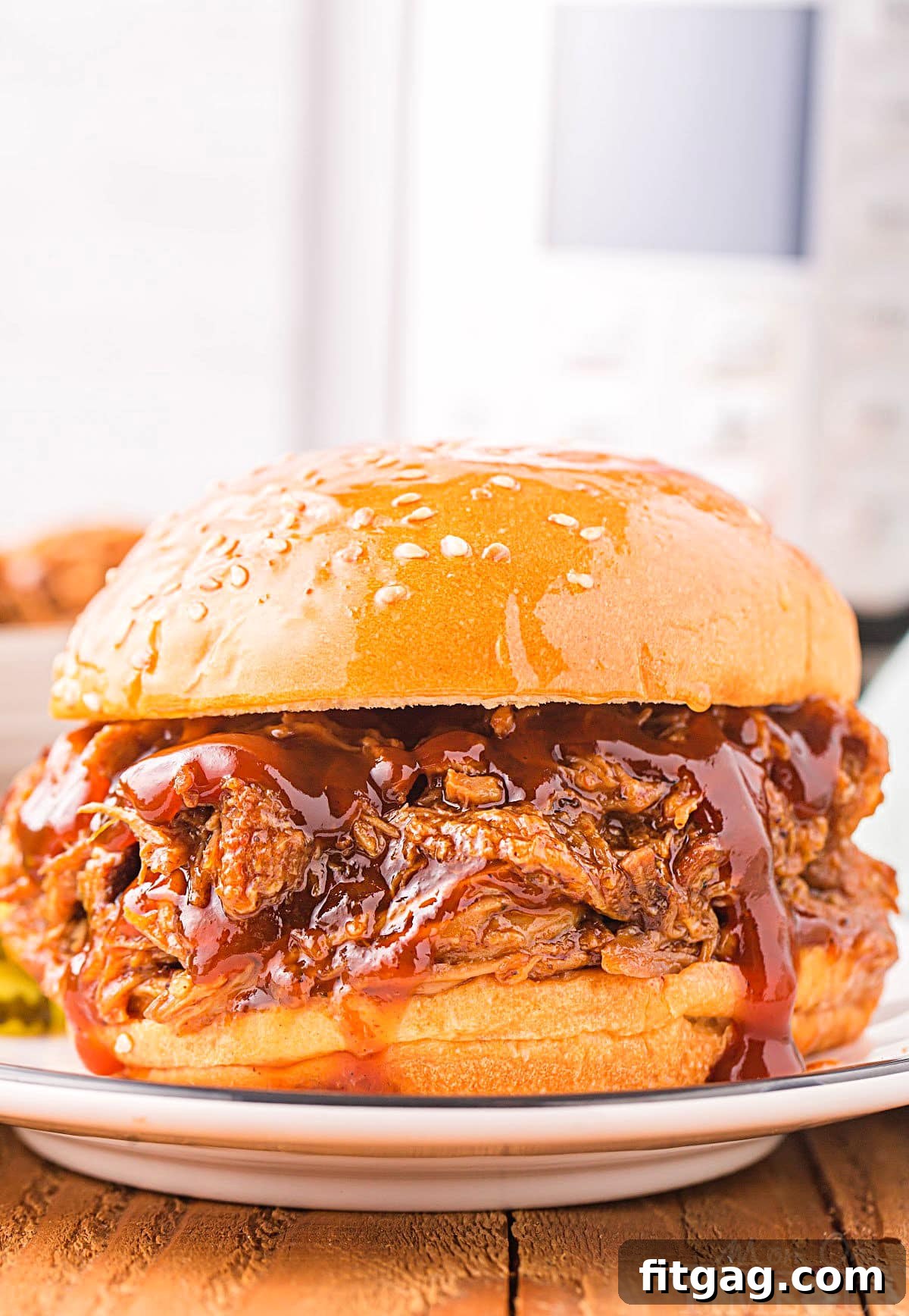 A delectable Instant Pot pulled pork sandwich with fresh toppings, ready to be enjoyed, with an Instant Pot visible in the background.