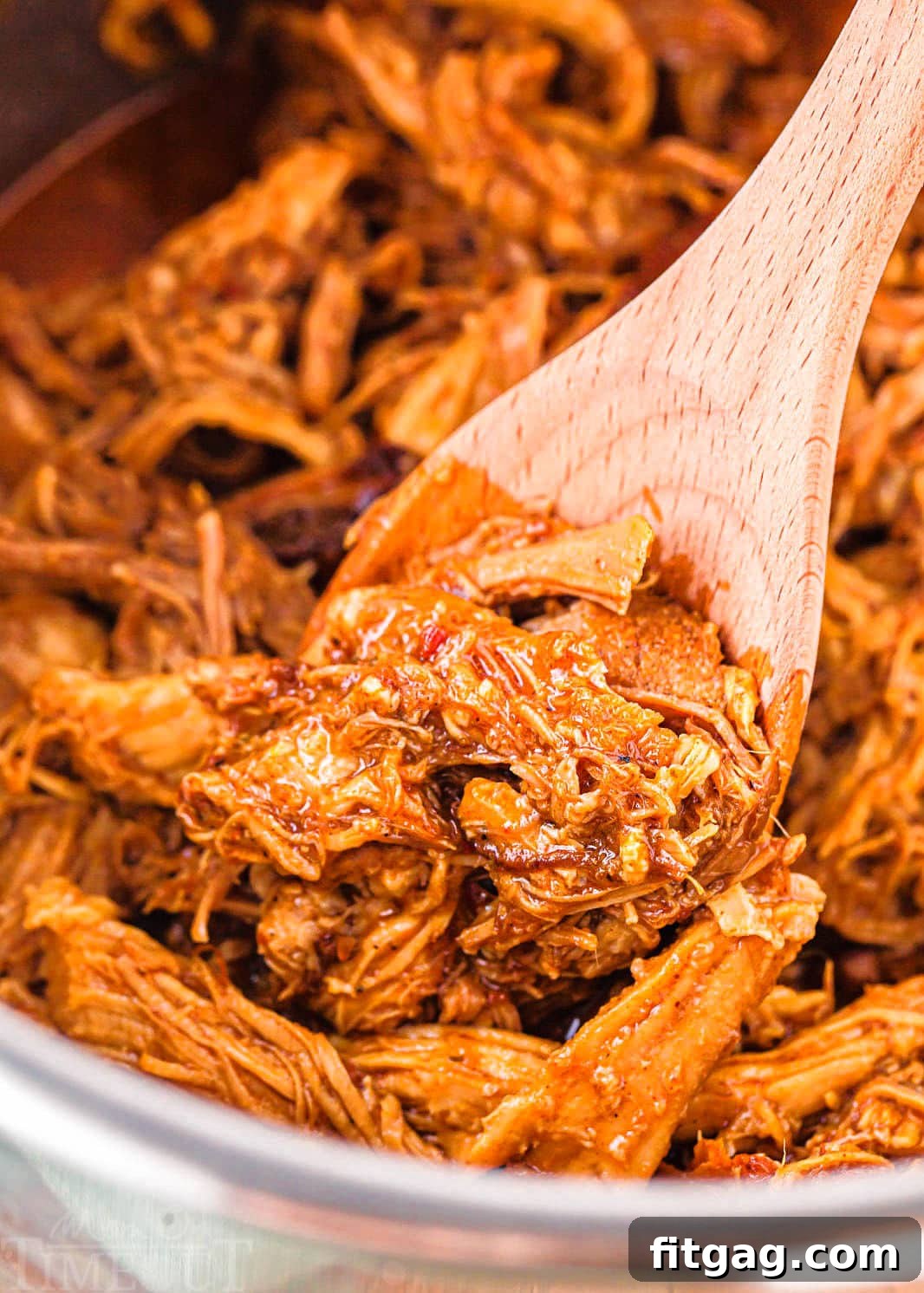 Effortless Instant Pot Pulled Pork 3 Shredded pulled pork perfectly cooked in an Instant Pot, stirred with a wooden spoon.