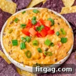 medium white bowl filled with rotel dip and topped with sliced green onions and diced tomatoes surrounded by blue and white corn tortilla chips.