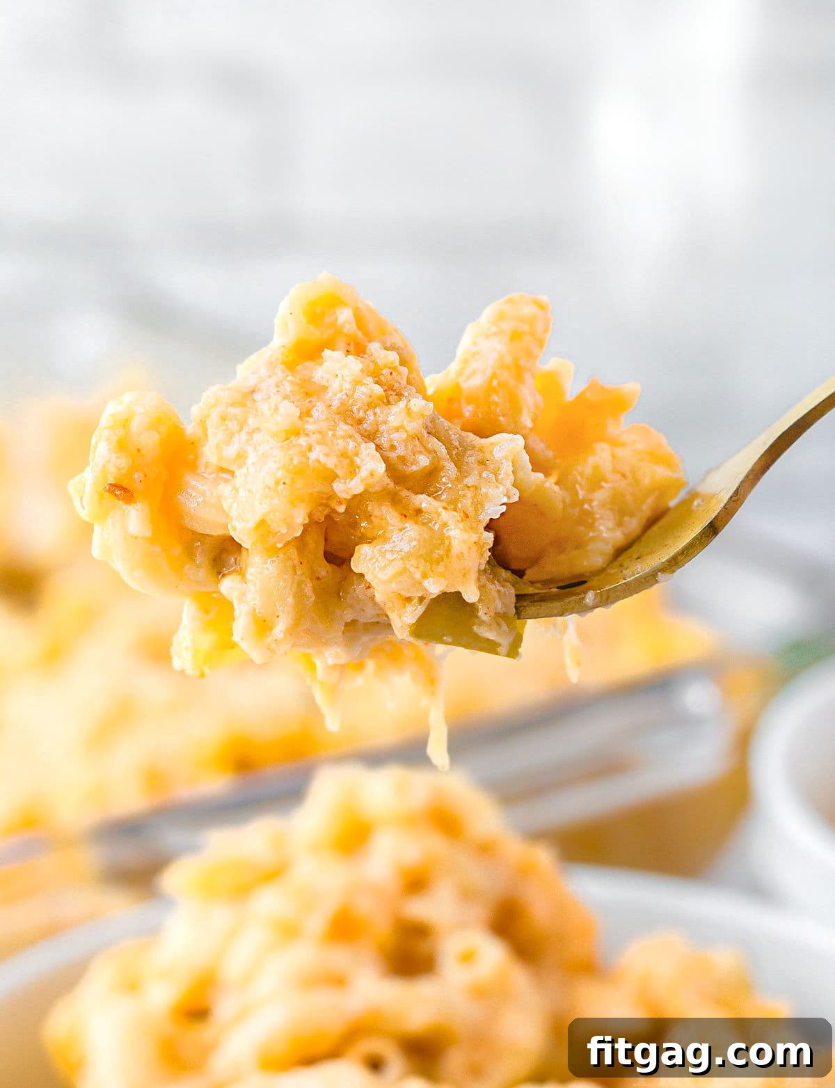 forkful of mac and cheese held above the bowl filled with the mac and cheese.