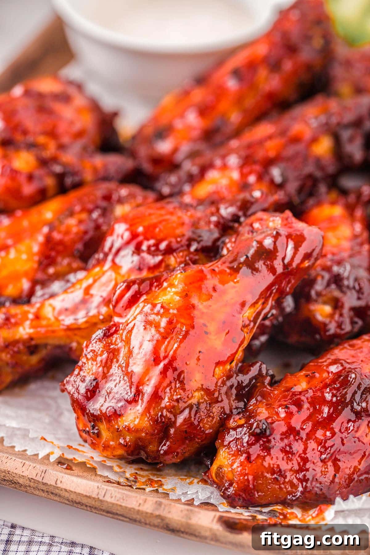 Air fryer chicken wings brushed with BBQ sauce, ready to be served on a rustic wooden board, garnished with fresh herbs.