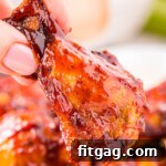 hand holding a chicken wing made in the air fryer and brushed with barbecue sauce.