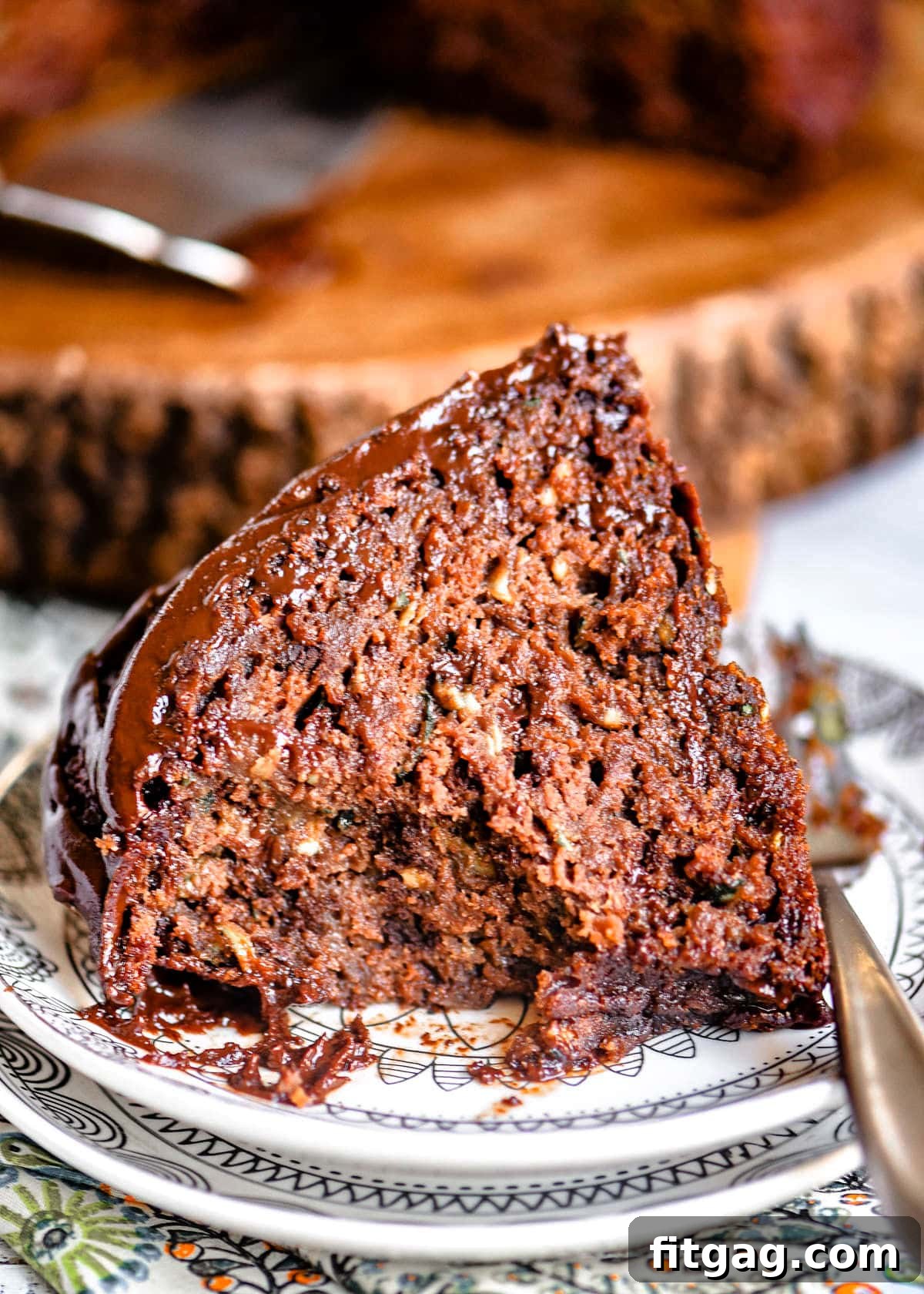 Decadent Chocolate Zucchini Cake 6 slice of cake with a couple bites taken sitting on a white small plate.