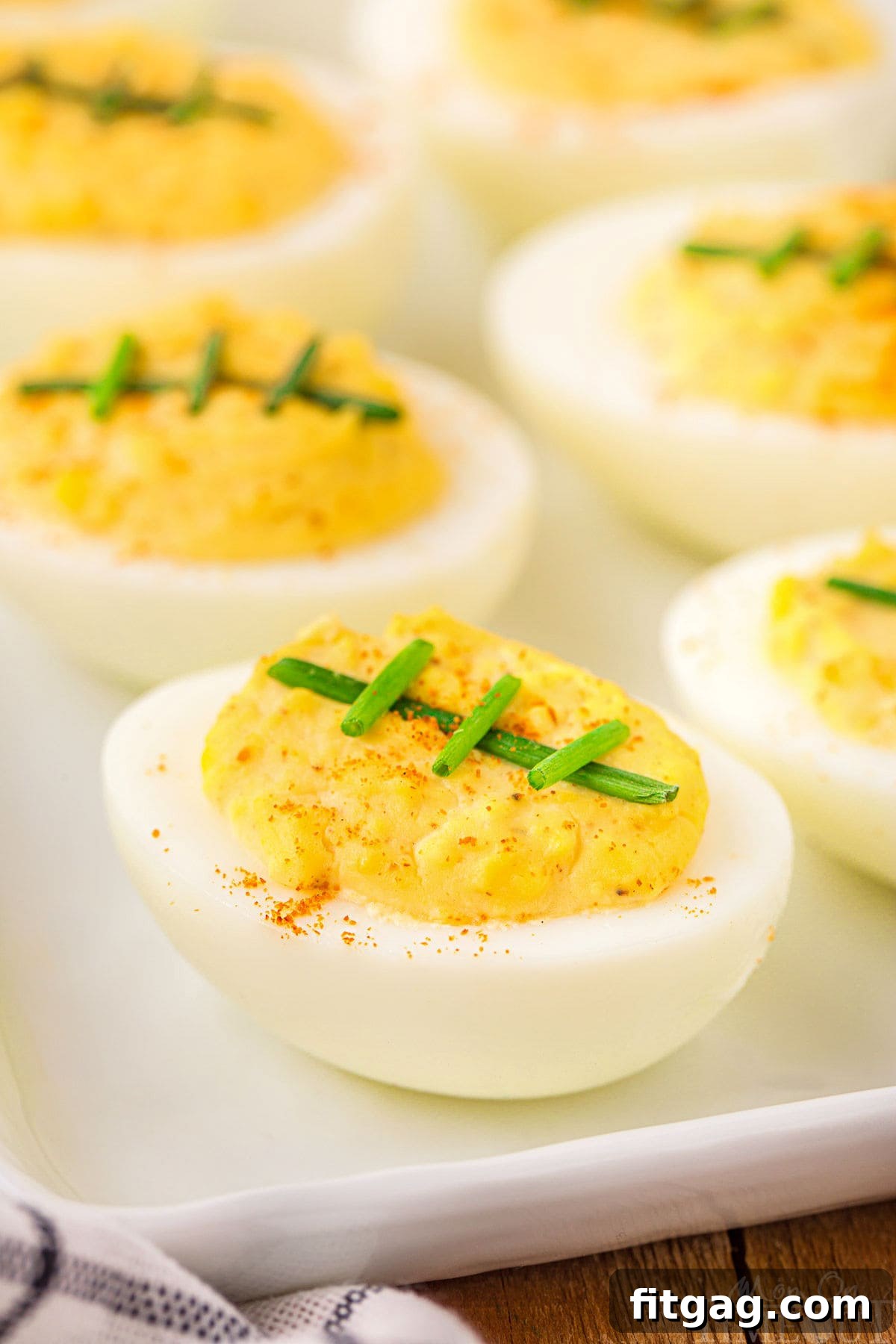 white plate of deviled eggs topped with chives. ready for a football party.