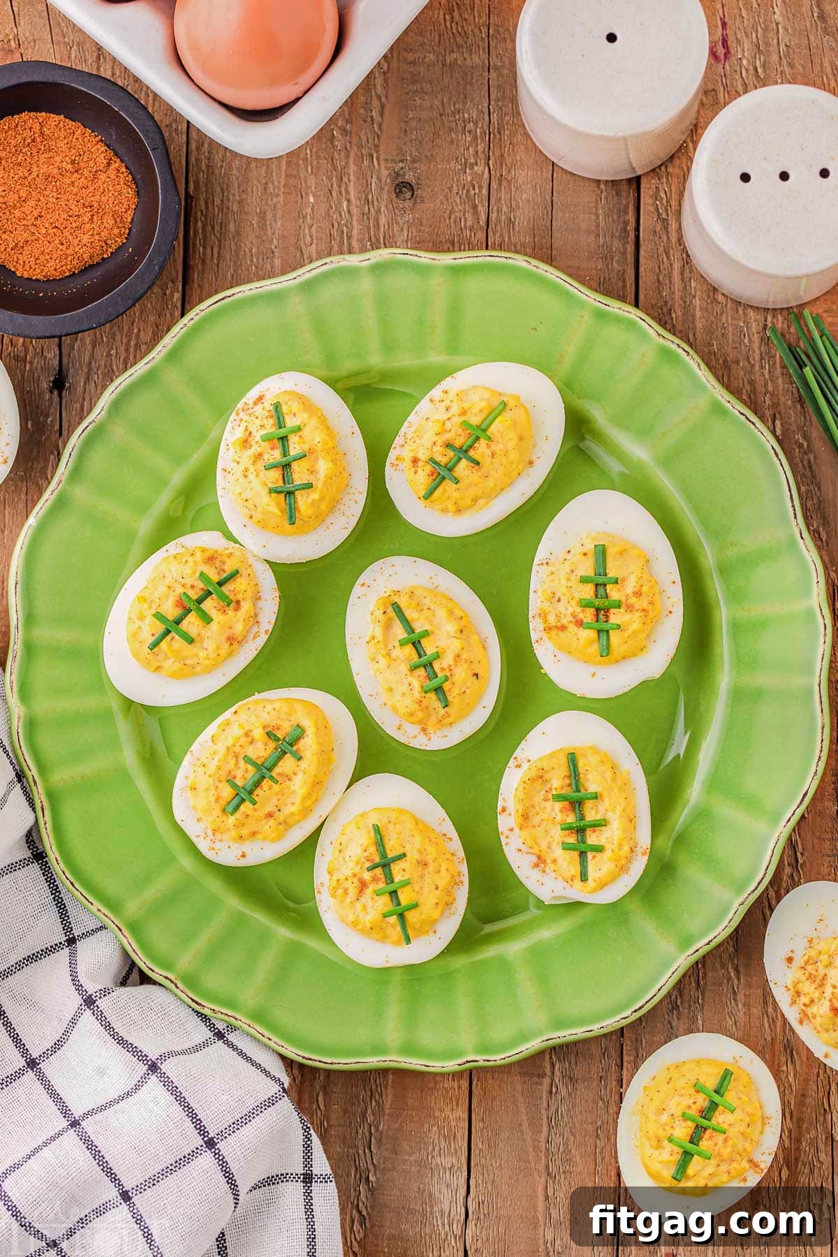 top down look at green plated loaded with deviled eggs that look like footballs.