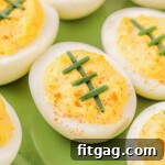 A vibrant green plate showcasing football deviled eggs, artfully decorated with chive laces, capturing the essence of game day festivities.