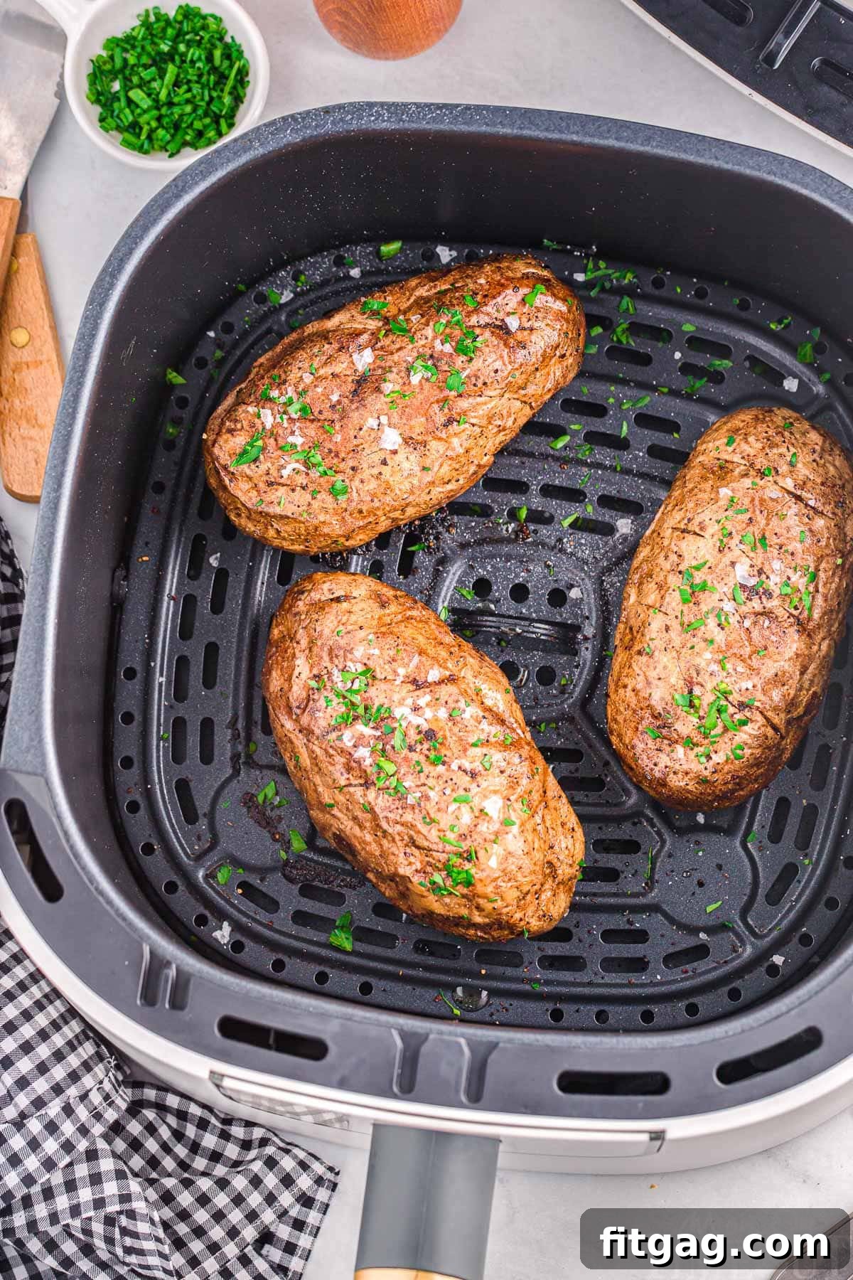 Top-down view of three medium-sized russet potatoes perfectly arranged in an air fryer basket, ready for cooking.