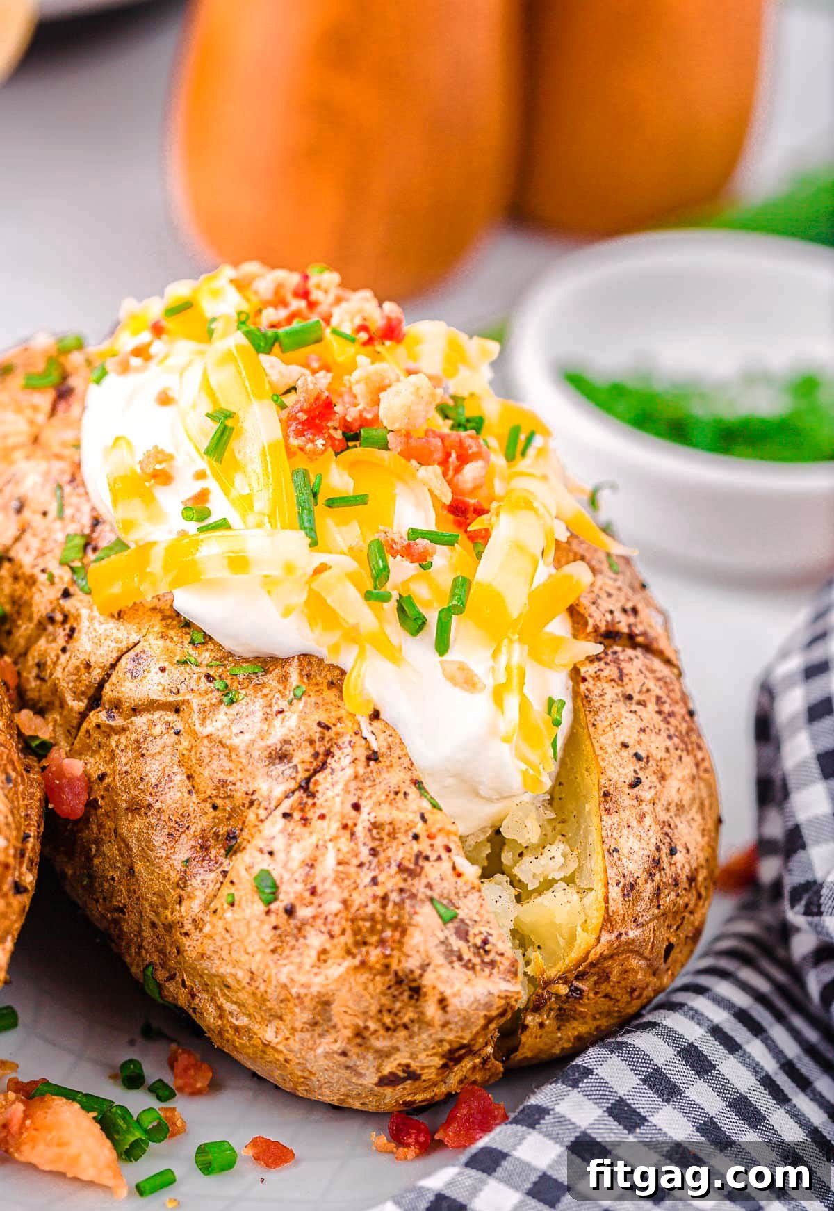 A fully loaded air fryer baked potato, generously topped with sour cream, shredded cheese, crispy bacon bits, and fresh chives, ready to be enjoyed.