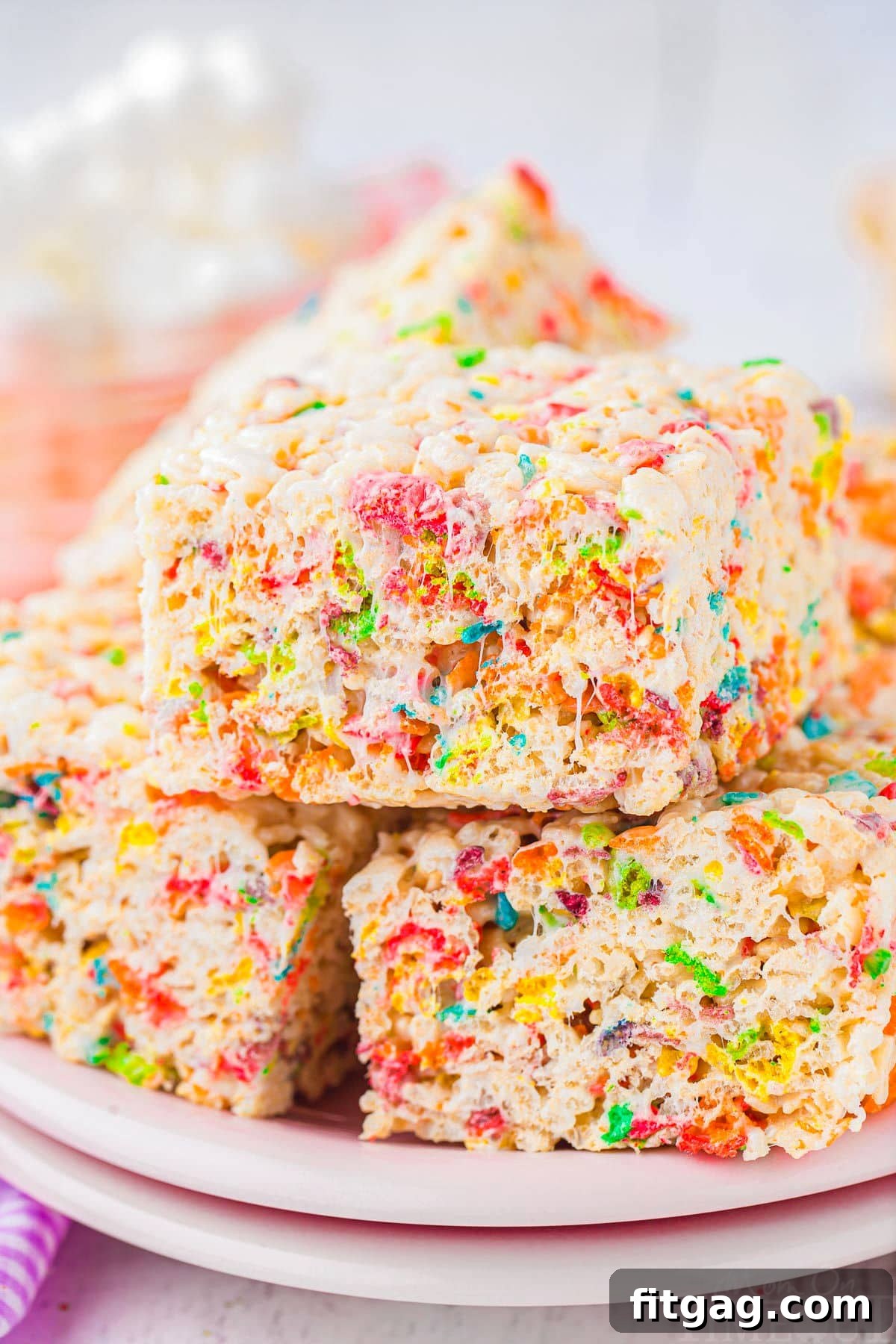 Vibrant Rainbow Krispie Bars 2 Vibrant Rainbow Rice Krispie Treats stacked on light pink plates, showcasing their colorful appeal.