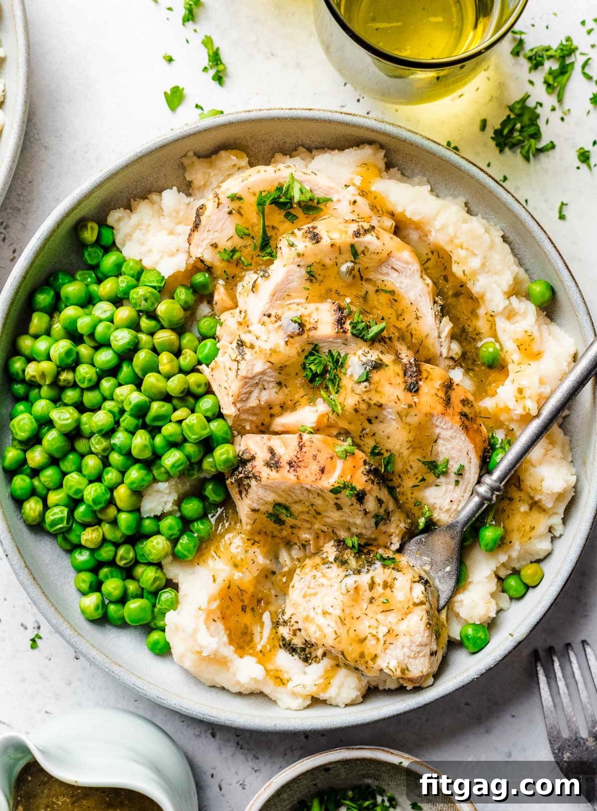 top down look at instant pot chicken breast sliced sitting on a bed of mashed potatoes with gravy over the top. green peas are also on the plate.