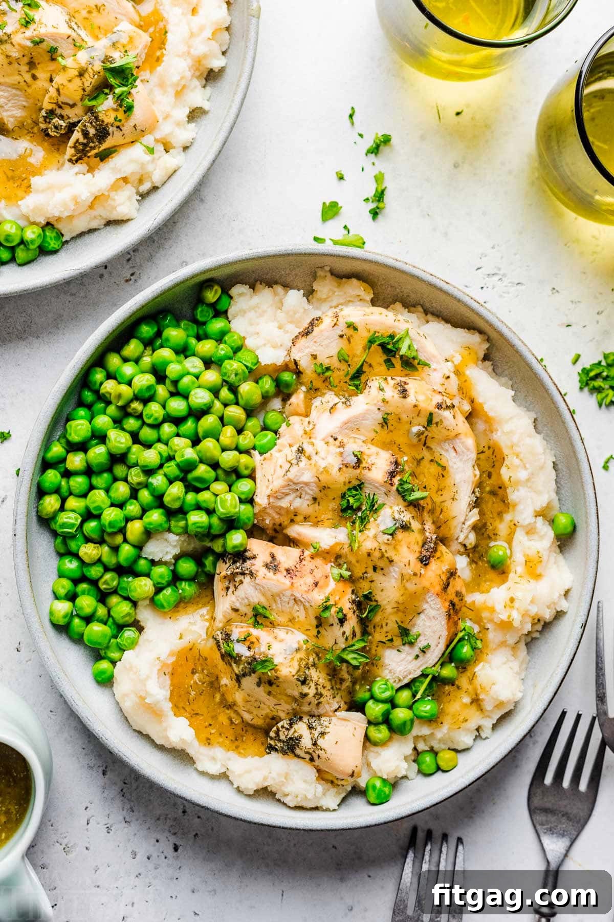 top down look at instant pot chicken breast sliced sitting on a bed of mashed potatoes with gravy over the top. green peas are also on the plate.