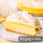 A slice of lemon meringue cheesecake with the rest of the cheesecake and lemon slices in the background.