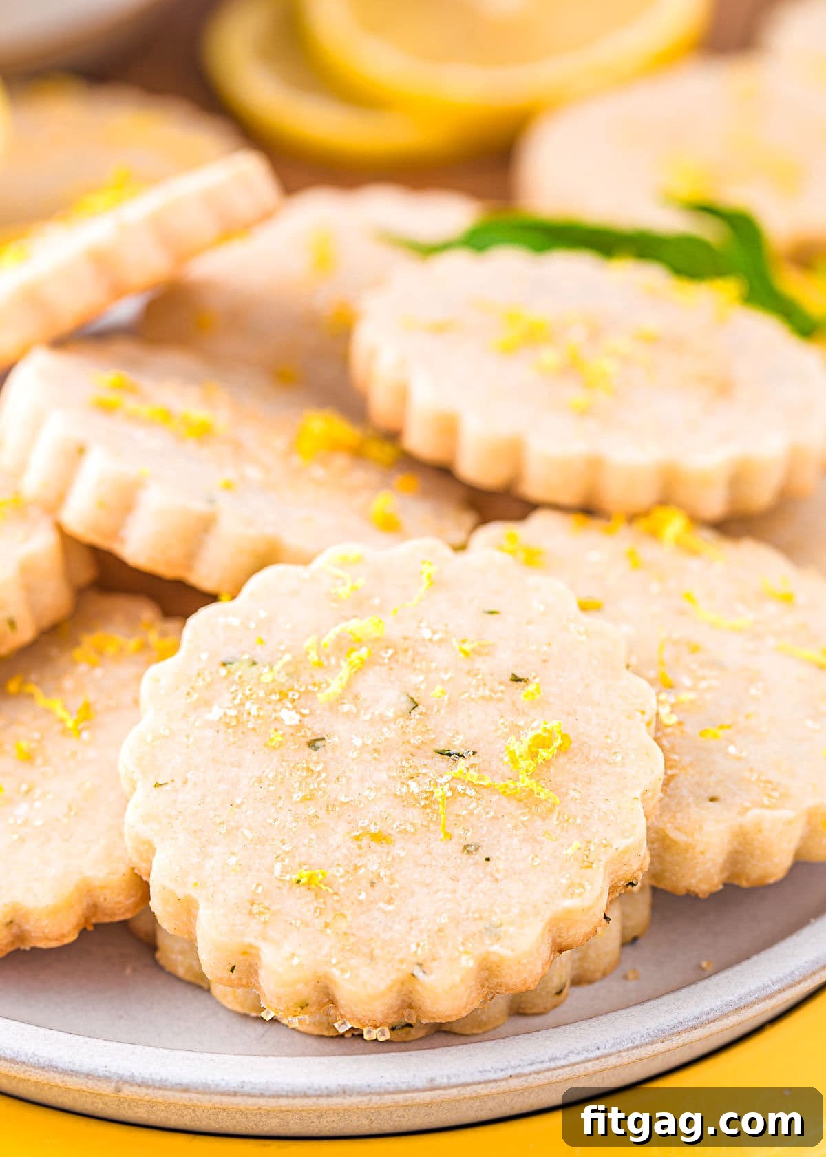 Zesty Lemon Basil Shortbread 2 Exquisitely arranged lemon basil shortbread cookies on a pristine white plate, adorned with delicate lemon zest and sparkling coarse sugar. Each cookie is perfectly golden, hinting at a buttery, crumbly texture.