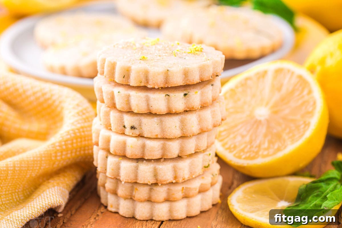 Zesty Lemon Basil Shortbread 5 A charming scene featuring a stack of golden lemon basil shortbread cookies placed in front of a white plate adorned with lemon halves and a vibrant yellow napkin. The setting evokes a fresh, inviting atmosphere.