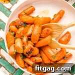 Honey glazed carrots on a round white plate garnished with fresh parsley. The plate is on a teal and white chevron tile surface.